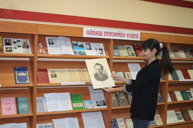 Библиотекарь Ольга Тимофеева знакомит читателей с новым стендом книг Якова Ухсая